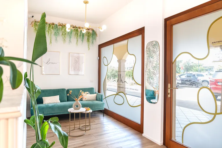 L'ingresso dello studio con divano verde, piante e specchi decorati