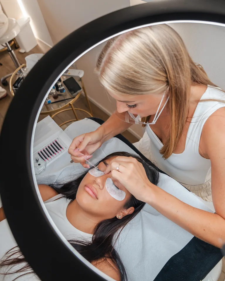 Le mani di una lash artist applicano le extension una a una